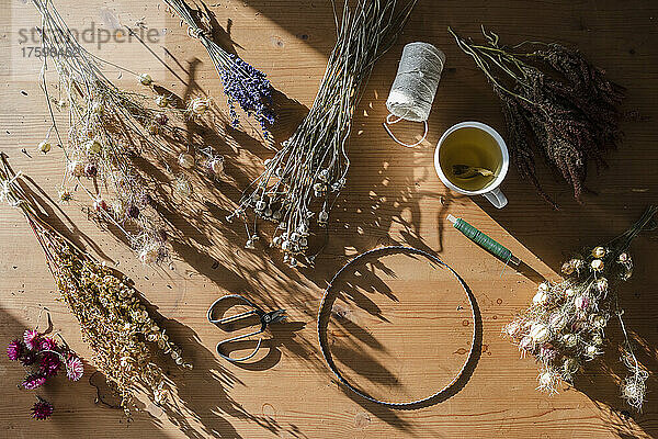 Studio shot of scissors  wire  thread and various dried flowers ready to be weaved into wreath