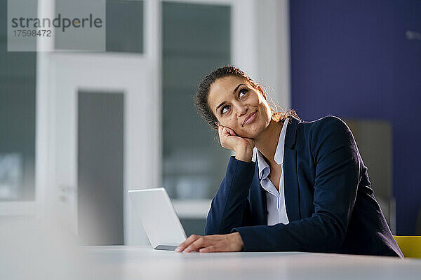 Geschäftsfrau mit Tablet-PC träumt im Büro