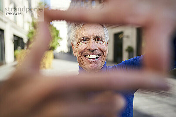 Cheerful senior man making finger frame