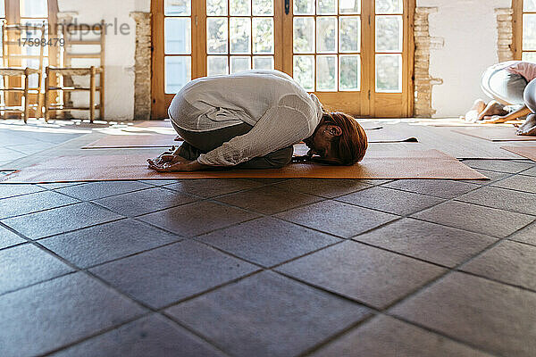 Woman practicing yoga on mat in health club