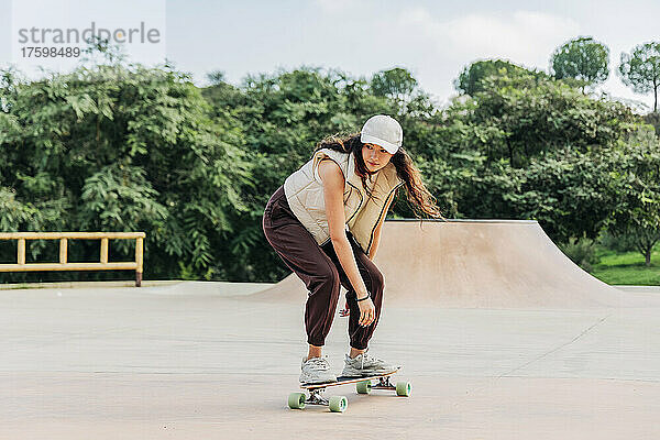 Junge Frau fährt Skateboard auf Sportrampe