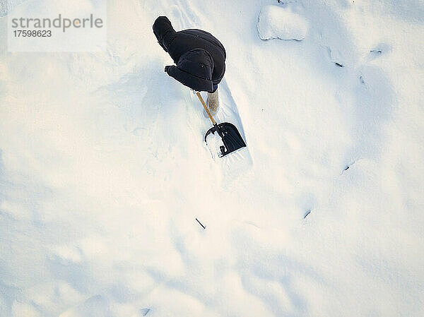 Woman cleaning snow with snow shovel in winter