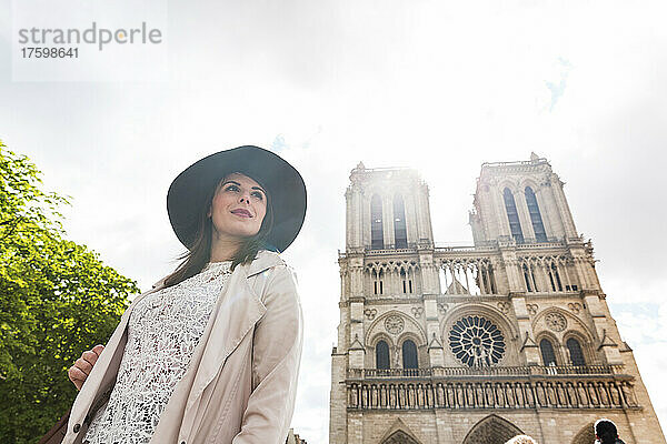 Junge Frau mit Hut in der Kathedrale Notre Dame im Urlaub