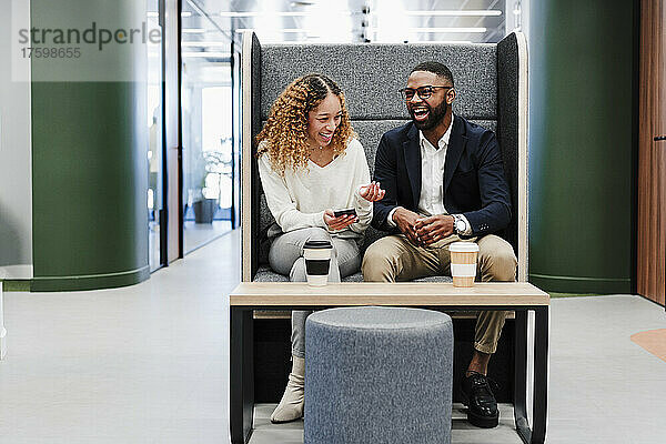 Zufriedene Geschäftskollegen sitzen bei der Kaffeepause im Coworking-Büro auf dem Sitz