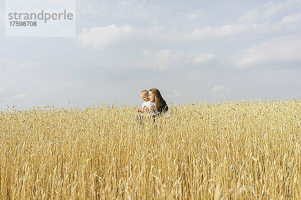 Junge Frau mit Sohn steht im Weizenfeld