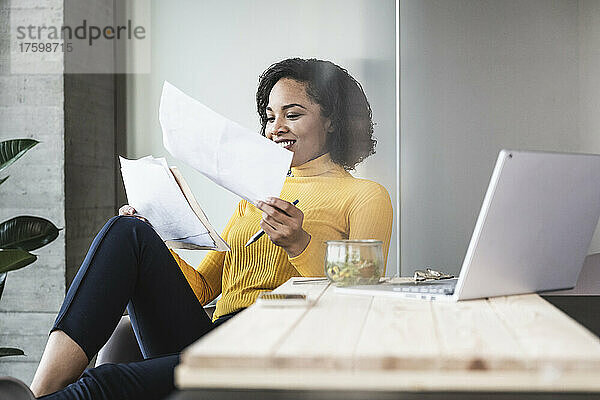 Lächelnde Geschäftsfrau analysiert Dokumente im Büro