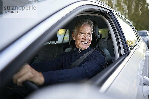 Lächelnder älterer Mann  der Auto fährt
