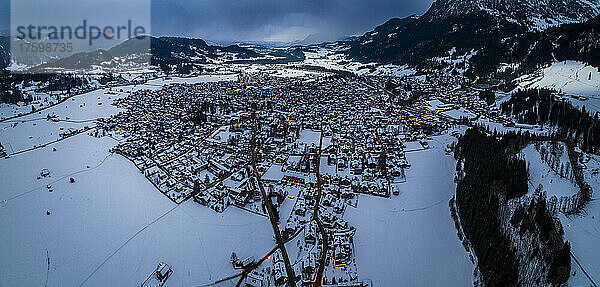 Germany  Bavaria  Oberstdorf  Helicopter panorama of snow covered town in Allgau Alps at dusk