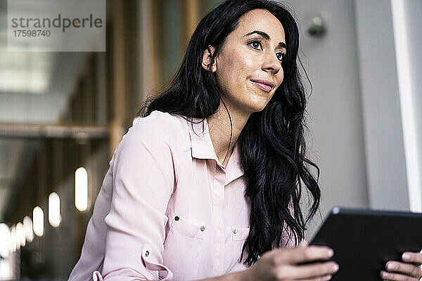 Geschäftsfrau mit Tablet-PC sitzt im Coworking-Büro