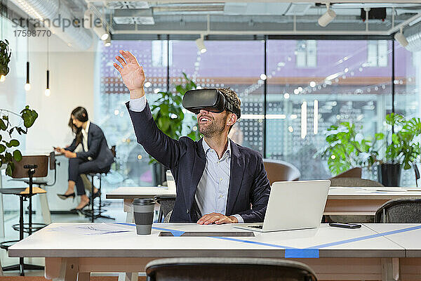 Manager trägt VR-Brille und gestikuliert im modernen Büro