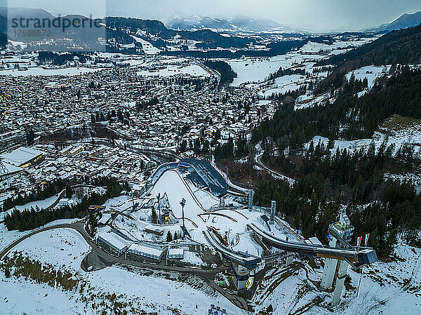 Germany  Bavaria  Oberstdorf  Helicopter view of snow covered town in Allgau Alps with ski jumping ramp in foreground