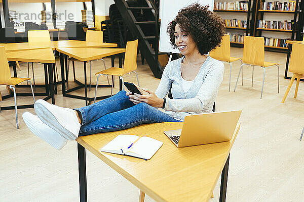 Geschäftsfrau benutzt Smartphone am Schreibtisch im Büro