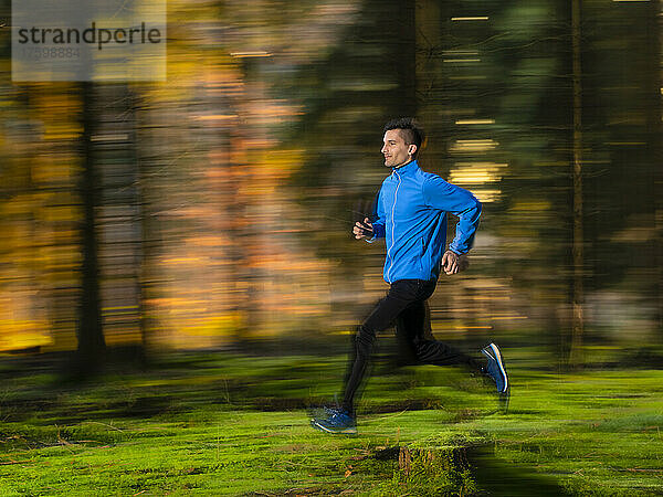 Dedicated young man jogging in forest