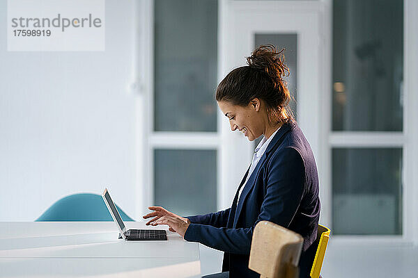 Lächelnde Geschäftsfrau benutzt Tablet-PC am Schreibtisch
