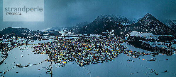 Germany  Bavaria  Oberstdorf  Helicopter panorama of snow covered town in Allgau Alps at dusk