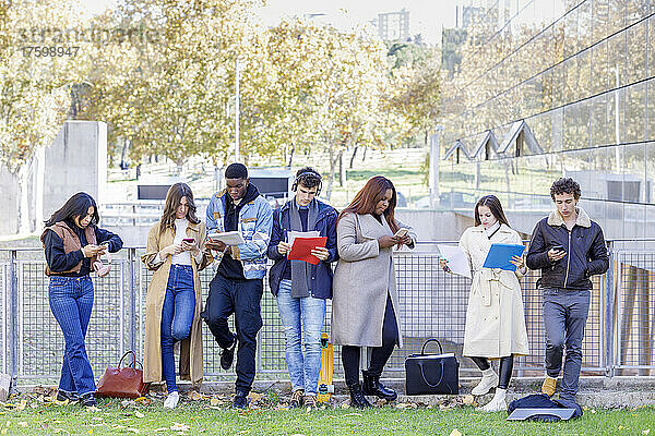 Studenten lernen und nutzen Smartphones am Geländer auf dem Campus