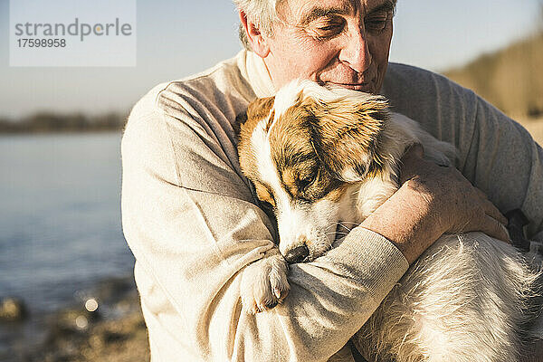 Älterer Mann umarmt Hund an sonnigem Tag