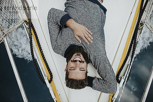 Lächelnder junger Mann  der auf einem Segelboot liegt