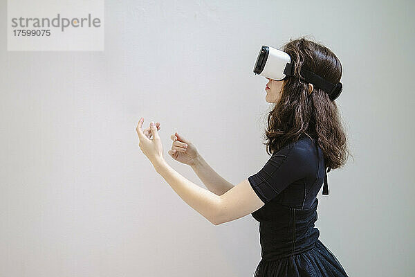 Junge Frau mit VR-Brille gestikuliert im Studio