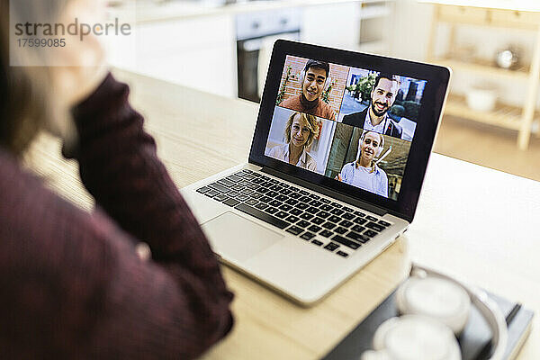 Freelancer doing video call with colleagues on laptop at home