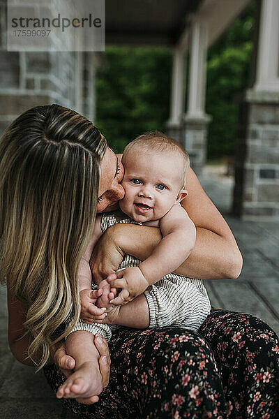 Zärtliche Mutter küsst ihren süßen Sohn auf der Veranda