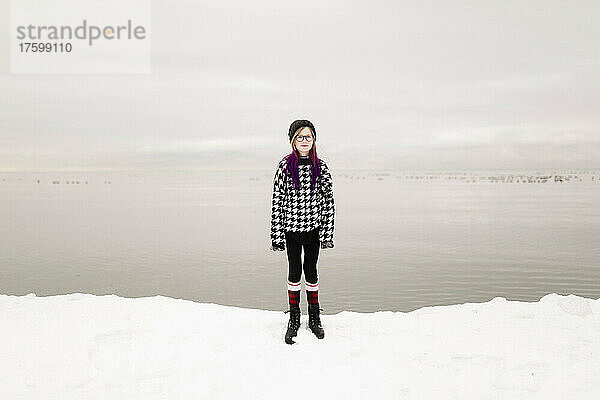 Mädchen mit Brille steht im Winter am See