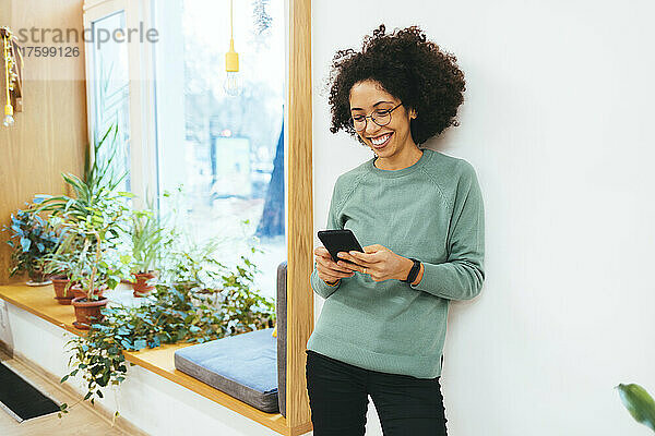 Smiling woman texting on mobile phone at home