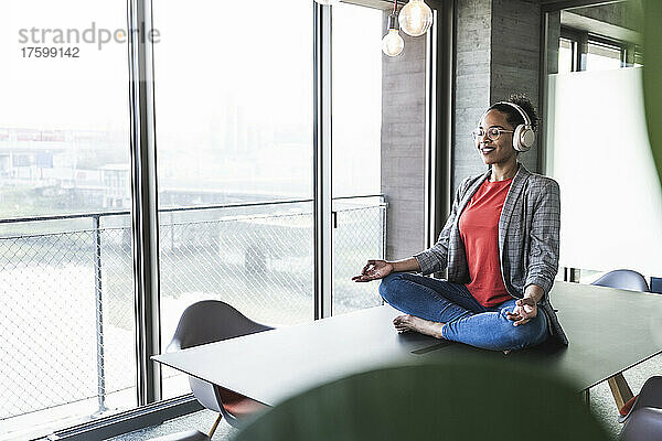 Geschäftsfrau hört Musik und meditiert am Arbeitsplatz