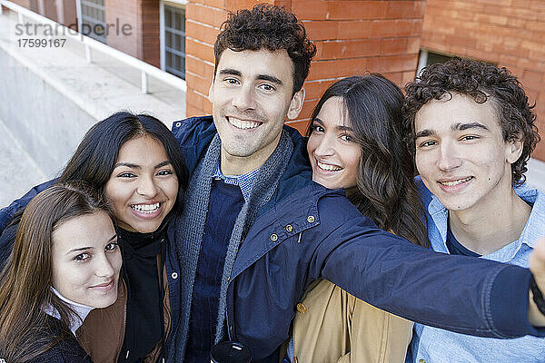 Lächelnde  gemischtrassige Freunde  die ein Selfie auf dem Universitätscampus machen