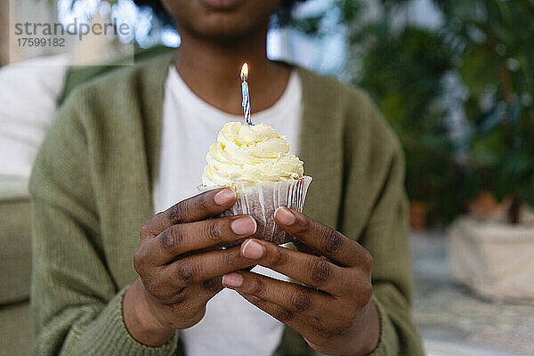 Junge Frau mit Kerze auf Cupcake am Geburtstag