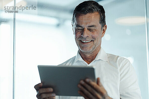 Lächelnder Geschäftsmann mit Tablet-PC im Büro