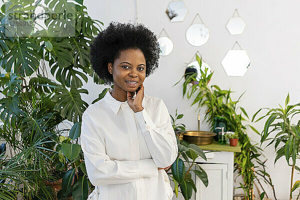 Afro-junge Frau steht zu Hause neben Pflanzen