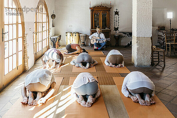 Musiker spielt vor Leuten  die im Yoga-Studio trainieren