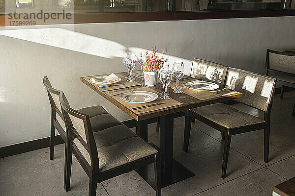 Tisch mit Geschirr und Gläsern neben Stühlen im Restaurant