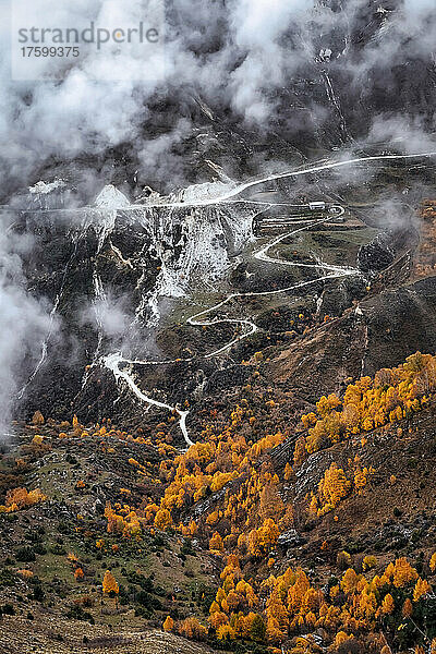 Road winding across mountainous landscape of North Caucasus on foggy autumn day