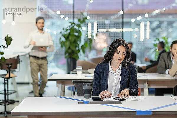 Junger Manager prüft Dokument am Schreibtisch im Coworking Space