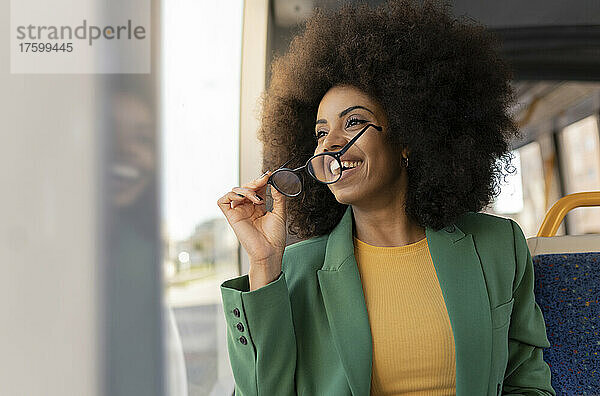Glückliche Geschäftsfrau mit Brille in der Straßenbahn