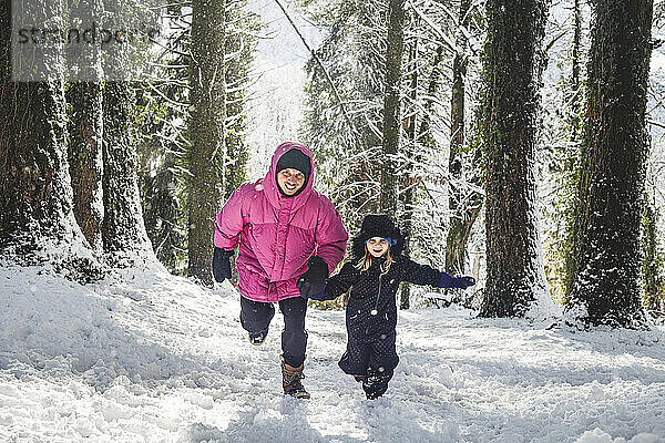 Vater und Tochter laufen auf Schnee und genießen den Wald