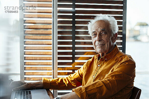 Älterer Mann sitzt mit Laptop am Hausboot