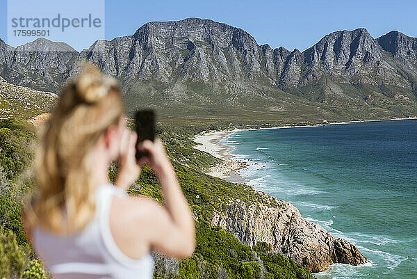 Junge Frau fotografiert an einem sonnigen Tag Berge per Smartphone