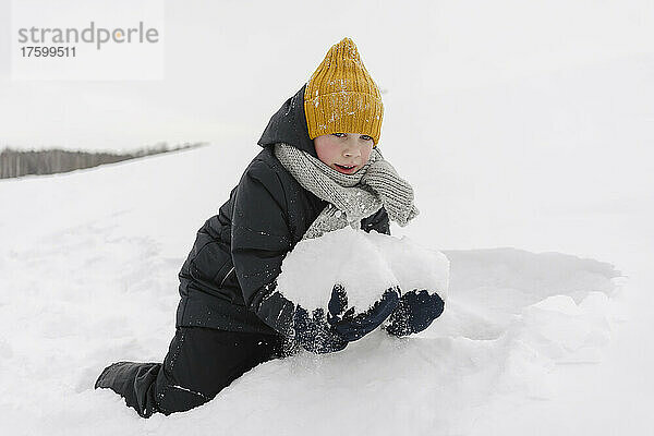 Junge spielt im Winter mit Schnee