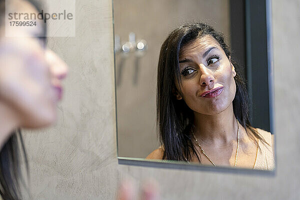 Beautiful woman puckering lips looking at mirror