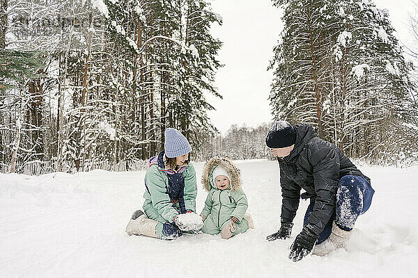 Glückliche Familie  die im Winter mit Schnee spielt
