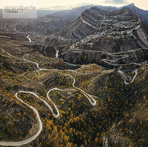 Russia  Dagestan  Gunib  Winding mountain road in autumn with Mount Gunib and village in background