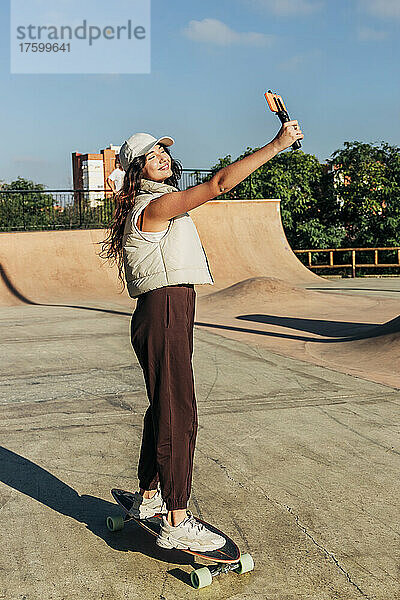 Junge Frau macht Selfie mit Smartphone im Skateboardpark