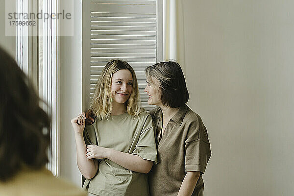 Smiling mother and daughter standing in living room