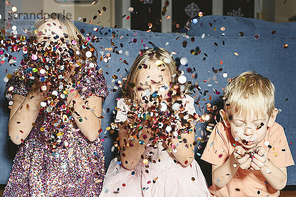 Siblings blowing confetti at home