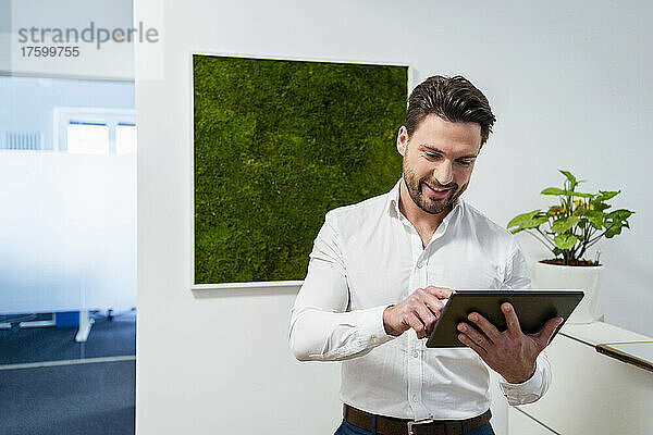 Lächelnder Geschäftsmann mit Tablet-PC im Büro