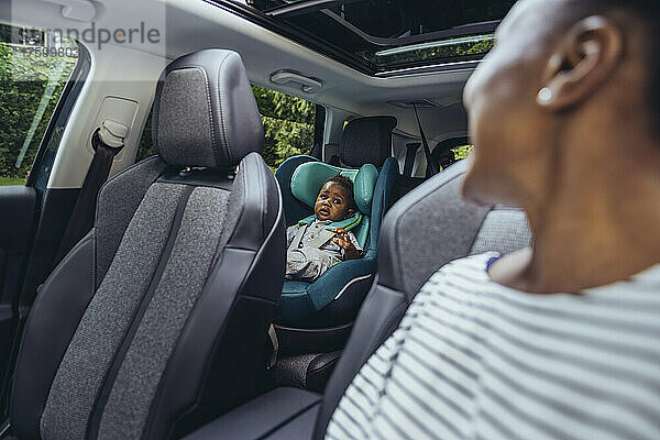 Mutter blickt auf kleinen Jungen  der im Auto sitzt