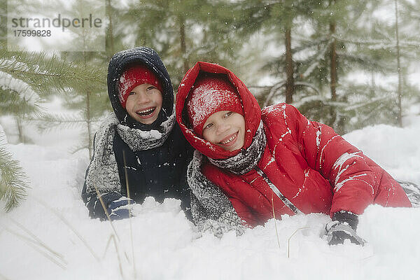 Glückliche Zwillingsbrüder genießen den Winter im verschneiten Wald